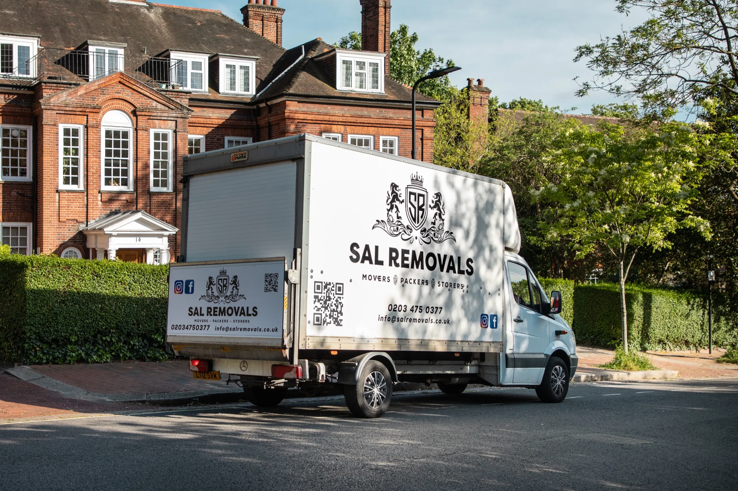 A branded Sal Removals Luton van parked at the kerb outside a red-brick block