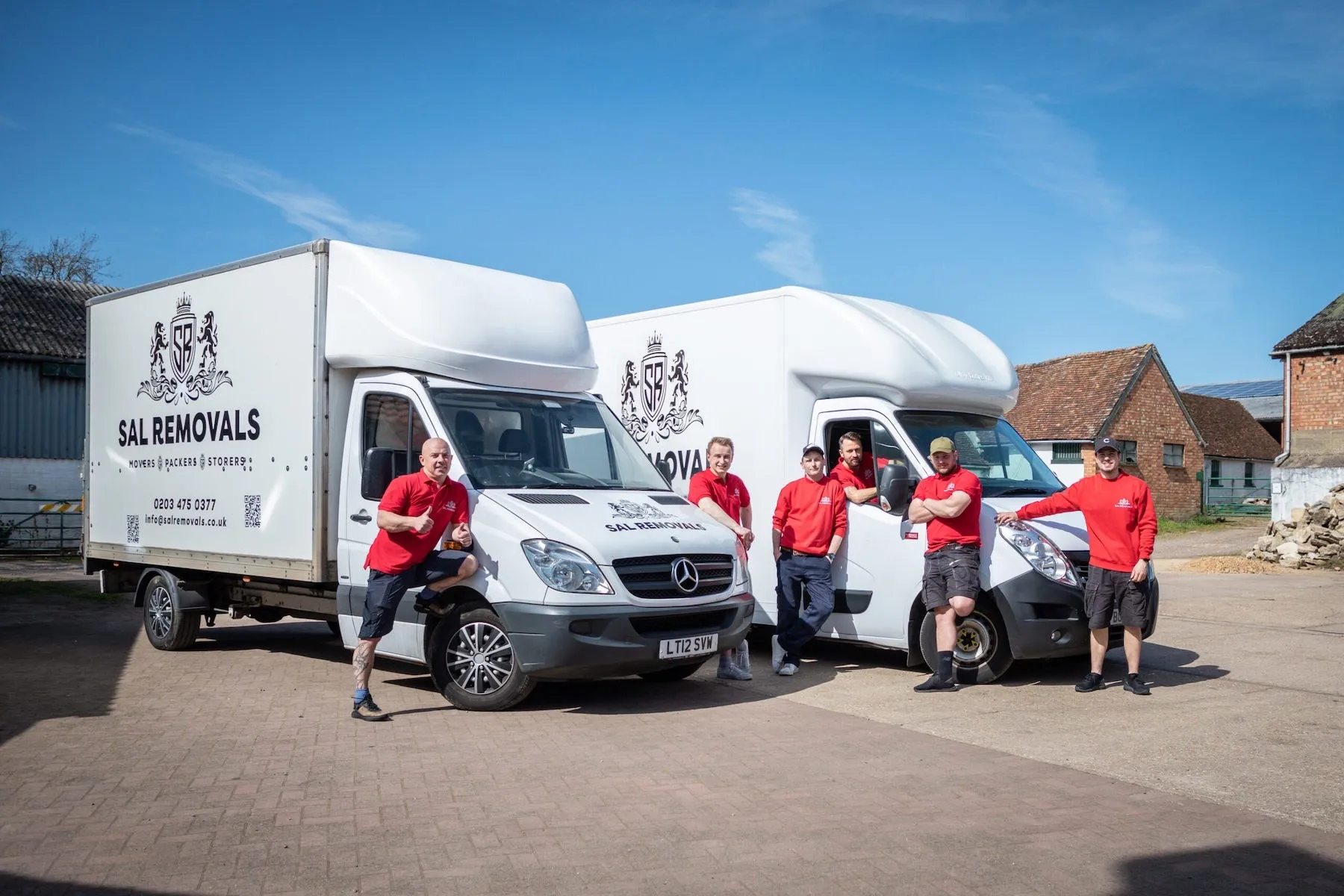 Six Sal Removals crew with two branded Luton vans in the yard
